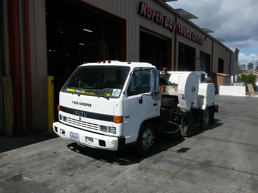 Isuzu sweeper truck in front of the shop